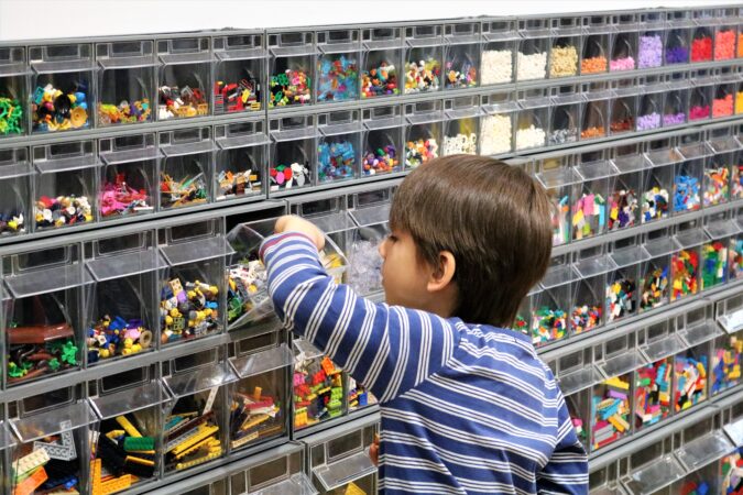 Chłopiec przy regale z klockami Lego